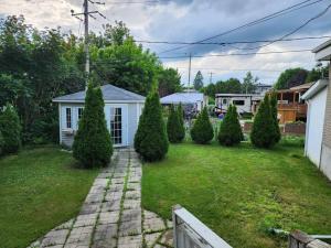 um quintal com uma casa branca e algumas árvores em Timeless Tranquility, a place near everything! em Longueuil