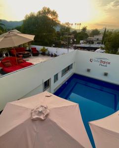 Una piscina con una sombrilla al lado de un edificio. en Posada Vista Tepoz, en Tepoztlán