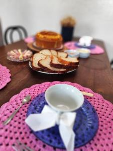 a wooden table with a plate of bread and a cup at Maga hospedagem in Penha