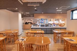un restaurante con mesas de madera y una cocina en Hotel Taiyo Nouen Furumitsu en Matsuyama