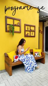 a woman sitting on a bench looking at her cell phone at Maga hospedagem in Penha