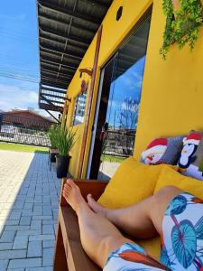 a woman laying on a bed with her feet on it at Maga hospedagem in Penha
