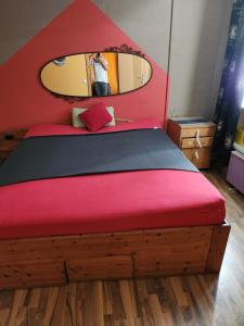 Schlafzimmer mit einem Bett mit einem roten Kopfteil und einem Spiegel in der Unterkunft Messeblick 1,2 km, Relax- App "Biene und Hummel" romantisch, Doppelzimmer gut & günstig in Hannover