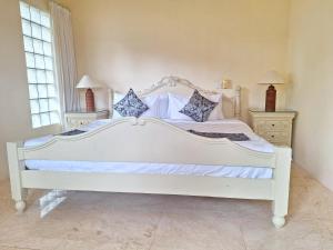 1 cama blanca en un dormitorio con 2 mesitas de noche en Arbathu Villa,,, en Ubud