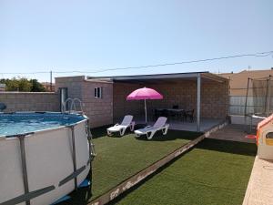 un patio trasero con piscina y sombrilla rosa en La Casa de la Abuela Jesús, en Sanlúcar de Barrameda