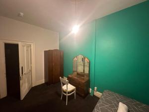 a bedroom with a green wall and a dresser and a mirror at Railway Hotel in South Rakaia