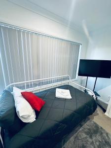 a bedroom with a bed with two red pillows at Private Room in Townhouse in Wollongong