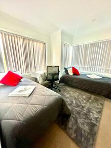 a bedroom with two beds and windows with red pillows at Private Room in Townhouse in Wollongong