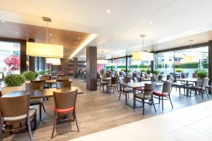 a restaurant with tables and chairs and windows at Holiday Inn Express Zürich Airport, an IHG Hotel in Rümlang