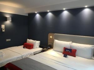 two beds in a hotel room with two red pillows at Holiday Inn Express Zürich Airport by IHG in Rümlang