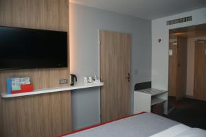 a hotel room with a bed and a flat screen tv at Holiday Inn Express Zürich Airport, an IHG Hotel in Rümlang