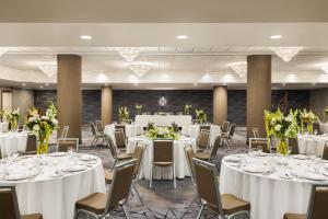 um salão de banquetes com mesas brancas e cadeiras com flores em Crowne Plaza Toronto Airport, an IHG Hotel em Toronto