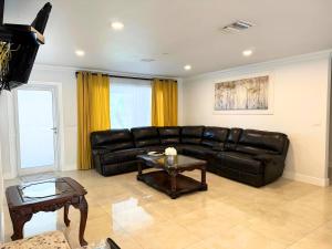 - un salon avec un canapé en cuir et une table dans l'établissement Spacious 4/4 Home Central To All Attractions, à Hollywood