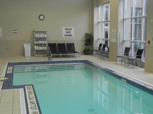 a swimming pool in a room with chairs and a clock at Holiday Inn Hotel & Suites London, an IHG Hotel in London