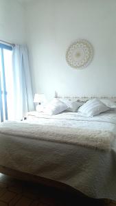 a bedroom with a large white bed and a window at Apartamento Piriápolis in Piriápolis