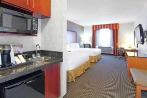 Holiday Inn Express Calgary South, an IHG Hotel في كالغاري: غرفة فندقية بسرير ومطبخ مع مغسلة