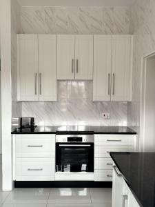 una cocina con armarios blancos y horno negro en holiday villa en Harare