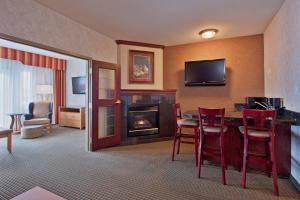 a hotel room with a fireplace and red chairs at Holiday Inn Express Calgary South, an IHG Hotel in Calgary