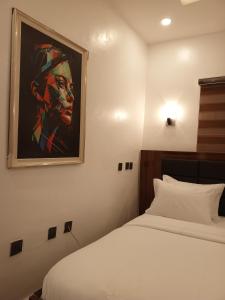 1 dormitorio con 1 cama y una pintura en la pared en Bristol 9 Lodge grill and bar, en Abuja