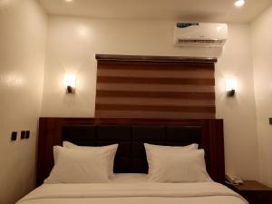 uma cama com uma cabeceira em madeira e 2 almofadas brancas em Bristol 9 Lodge grill and bar em Abuja