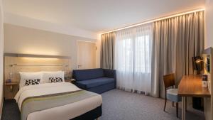 Holiday Inn Express Singen, an IHG Hotel في سينجين: غرفة فندق بسرير واريكة زرقاء