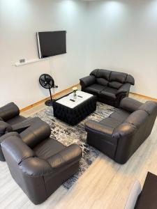 sala de estar con muebles de cuero y TV de pantalla plana en holiday villa en Harare