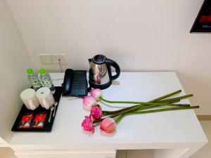 a white desk with flowers and a phone on it at Aodai Inn Saigon in Ho Chi Minh City