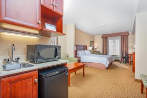 a hotel room with a bed and a kitchen with a television at Holiday Inn Express Hotel & Suites Clarington - Bowmanville, an IHG Hotel in Bowmanville