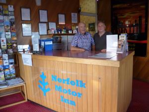 Ein Mann und eine Frau stehen an einem Tresen in einem Laden. in der Unterkunft Norfolk Motor Inn in Adelaide