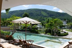 einen Pool mit Sonnenschirm und Stühlen und einen Berg in der Unterkunft Lotus Home Quảng Ngãi in Quảng Ngãi