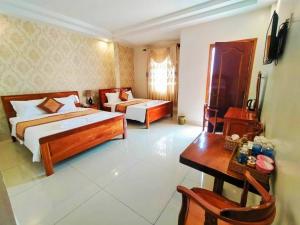 Habitación de hotel con 2 camas, mesa y escritorio en Khách Sạn Tường Vy, en An HÃ²a