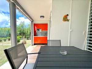 a patio with a table and a kitchen with red cabinets at Saranah Beach Resort - Wifi, Plage, Netflix in Grand-Bourg +3 photos