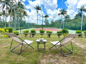 - deux chaises et une table sur un court de tennis dans l'établissement La Saranah - Blue Dream, Piscine, Plage, à Grand-Bourg