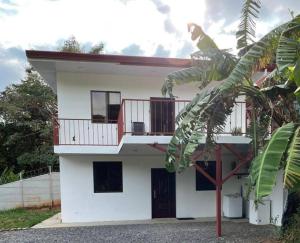 ein weißes Haus mit einem Balkon und einer Palme in der Unterkunft Esparza-PURA VIDA-Tu espacio tranquilo y acogedor. in Esparza
