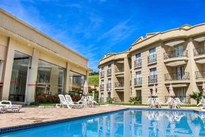 a hotel with a swimming pool in front of a building at Flat Amo Piscina Quartier Aldeia das Águas in Barra do Piraí