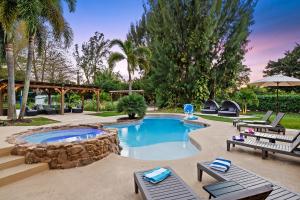 a swimming pool in a backyard with chairs and a table at Luxurious 8BR Dream Estate w Private Heated Pool in Pompano Beach