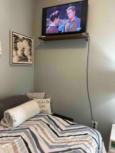 a flat screen tv hanging on a wall above a bed at Fancy studio private entrance in Selden