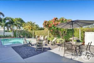 a table and chairs with an umbrella next to a pool at Modern 5BR with Heated Pool 5 min to Beach in Pompano Beach