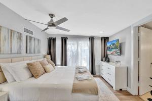 a white bedroom with a large bed with a ceiling fan at Modern 5BR with Heated Pool 5 min to Beach in Pompano Beach