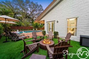 a backyard with chairs and a fire pit and a pool at Charming 9BR New-Build Home w Heated Pool & Games in Hollywood
