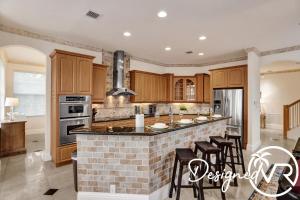 a kitchen with wooden cabinets and an island with bar stools at Gorgeous venetian home walk to beach with HOTTUB in Hollywood