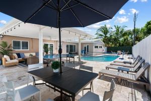 patio ze stołem i krzesłami oraz basenem w obiekcie 6BR Paradise: Pool Games & Relaxation w mieście Lighthouse Point