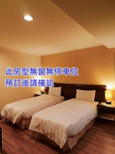 台南的住宿－文化信然，两张位于酒店客房的床,墙上有标志