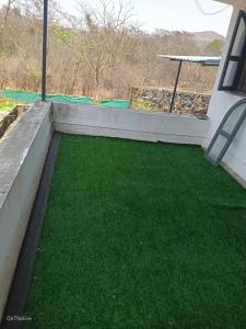 einen Balkon mit grünem Gras und einem Tisch in der Unterkunft OTE Dulis Den in Pune