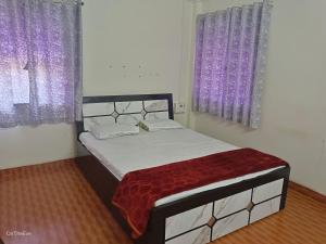 Bett in einem Schlafzimmer mit lila Vorhängen in der Unterkunft OTE Dulis Den in Pune