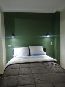 a bedroom with a large bed with a green wall at Inca´s Suite in Los Baños del Inca