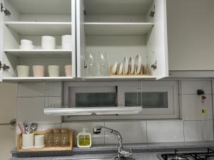 首爾的住宿－Gongdeok Stay，厨房配有带餐具和水槽的白色橱柜