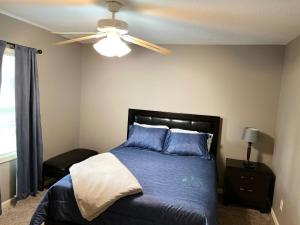 a bedroom with a bed with blue pillows and a ceiling fan at The Woodland Villa in Kansas City