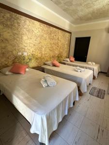 Zimmer mit 3 Betten und weißer Bettwäsche in der Unterkunft HOSTAL LAS GARZAS in Talara