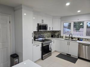 een keuken met witte kasten en een fornuis met oven bij 3 Bedroom Home away from Home in Calgary